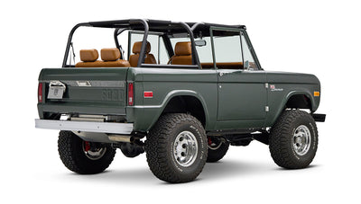 Classic Ford Bronco dark green rear right side view with open top and tan leather seats.