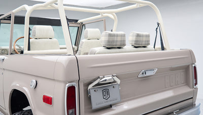Rear view of Classic Ford Bronco in dove gray with open roof and plaid headrests