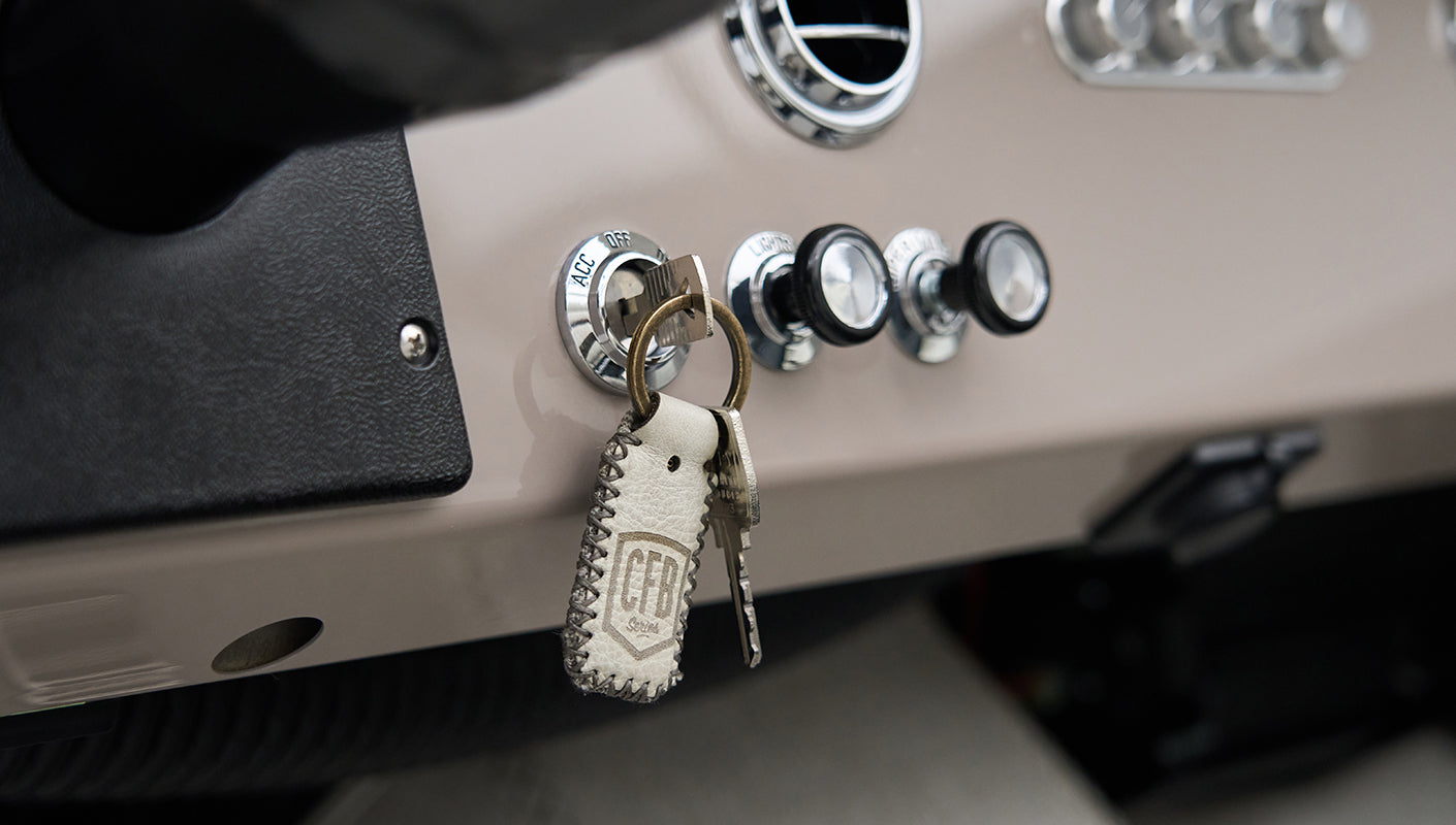 Ignition key with leather CFB keychain inserted in dashboard with control knobs