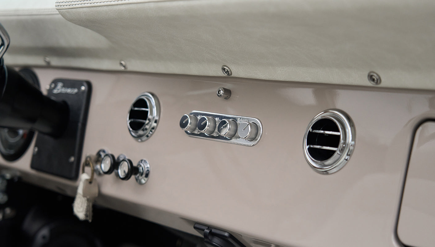 Dashboard of Classic Ford Bronco with round air vents and chrome climate control knobs