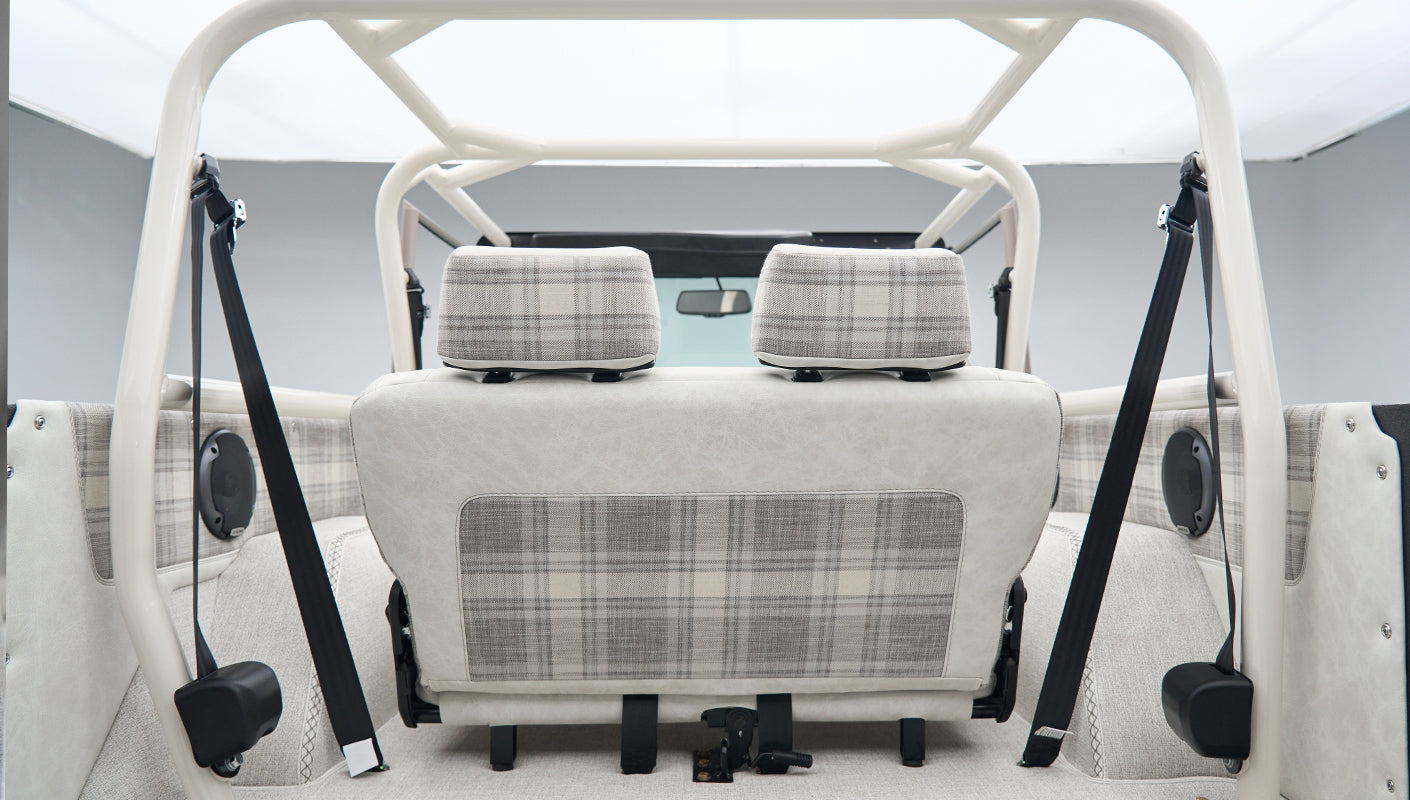 Rear view of Classic Ford Bronco interior with white and plaid seats and roll cage