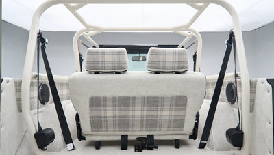 Rear view of Classic Ford Bronco interior with white and plaid seats and roll cage