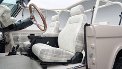 Passenger side interior of Classic Ford Bronco featuring plaid fabric seats and open door
