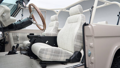 Passenger side interior of Classic Ford Bronco featuring plaid fabric seats and open door