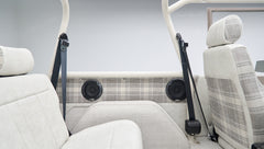 View of rear seat, plaid side panels, and black seat belts inside classic Ford Bronco