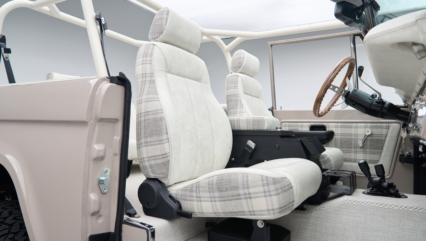 Close-up side view of front seat in Classic Ford Bronco with plaid fabric and seat belt