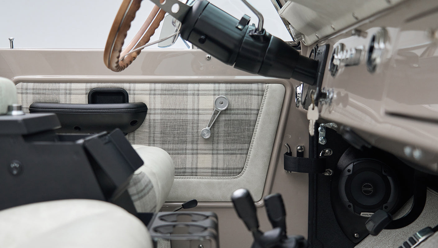 Classic Ford Bronco door interior panel with plaid fabric and manual window crank