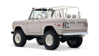 Rear-side view of Classic Ford Bronco in dove gray with white wheels and plaid seat covers