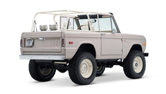Rear 3/4 view of Classic Ford Bronco in dove gray with white wheels and plaid upholstery