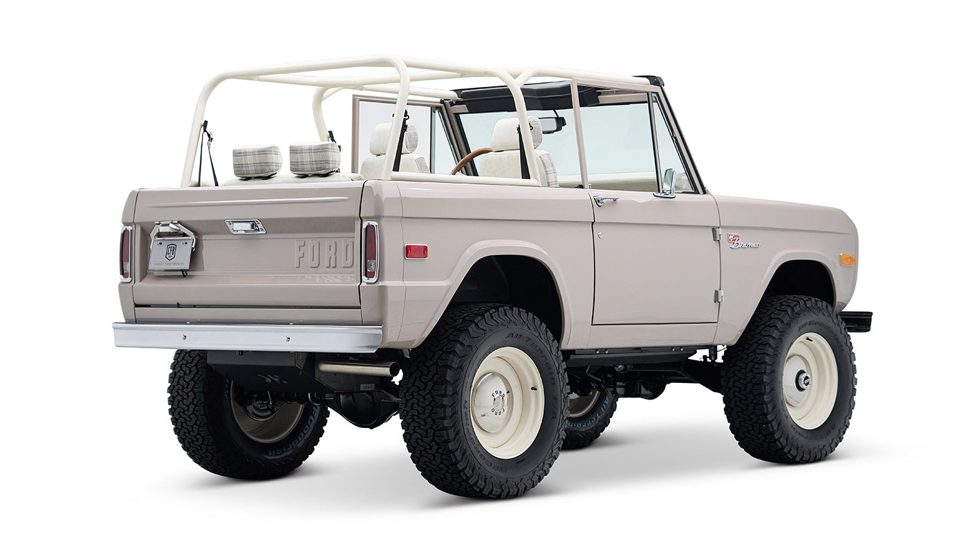 Rear 3/4 view of Classic Ford Bronco in dove gray with white wheels and plaid upholstery