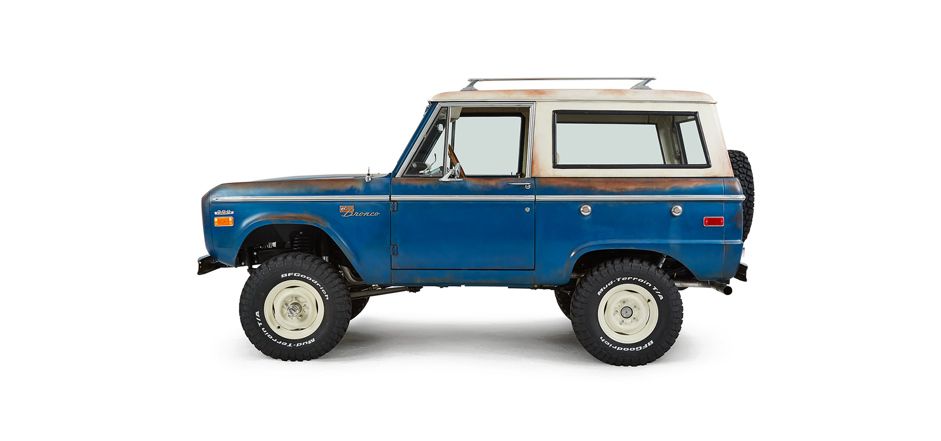 Classic Ford Bronco driver side profile with white roof and mounted spare tire