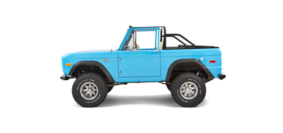 Side profile of blue Classic Ford Bronco driver's side with black fender flares and off-road tires.