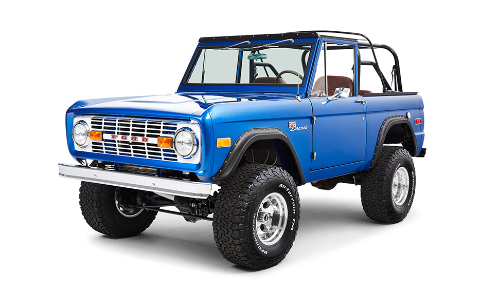 Classic Ford Bronco blue driver angled front view with round headlights and chrome bumper