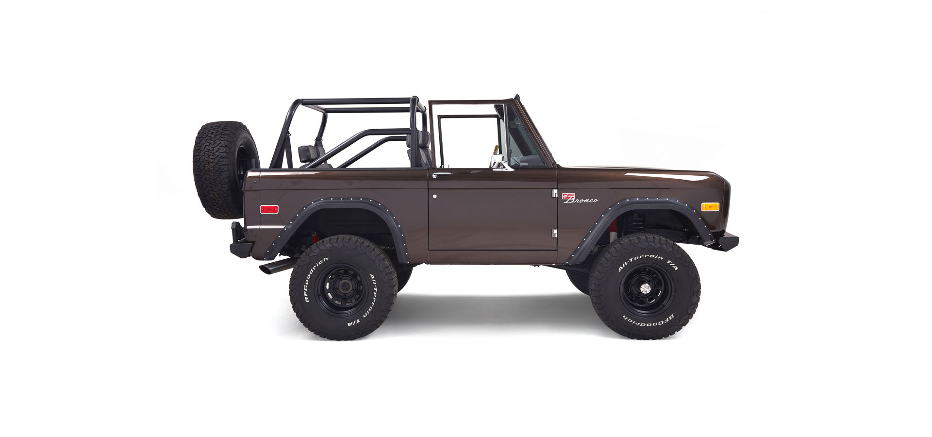 Side profile of a brown Classic Ford Bronco with open top and spare tire mounted on rear
