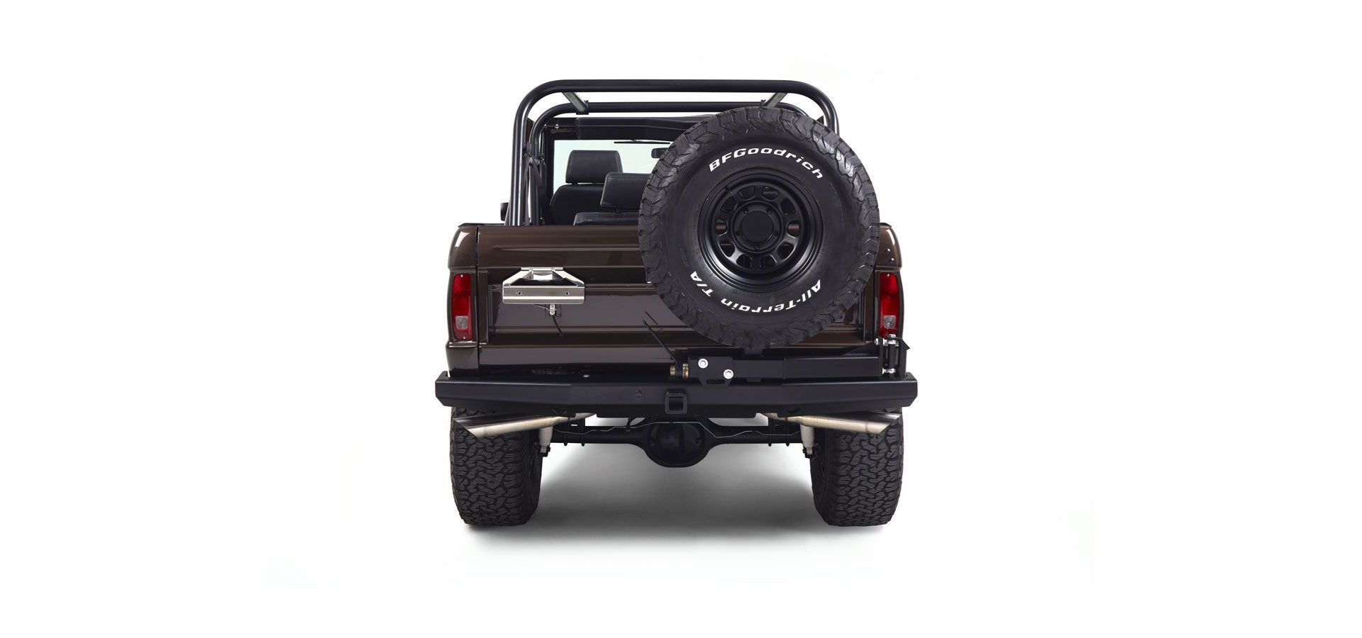 Rear view of a brown Classic Ford Bronco with spare tire on tailgate and dual exhaust pipes