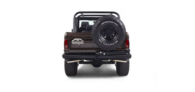 Rear view of a brown Classic Ford Bronco with spare tire on tailgate and dual exhaust pipes