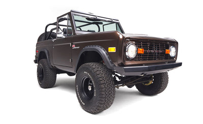 Front 3/4 view of a brown Classic Ford Bronco with headlights on and black wheels