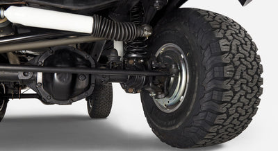 Undercarriage close-up showing wheel assembly, suspension spring, and axle of Classic Ford Bronco