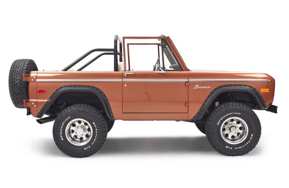 Side profile of brown Classic Ford Bronco with no doors and black roll cage