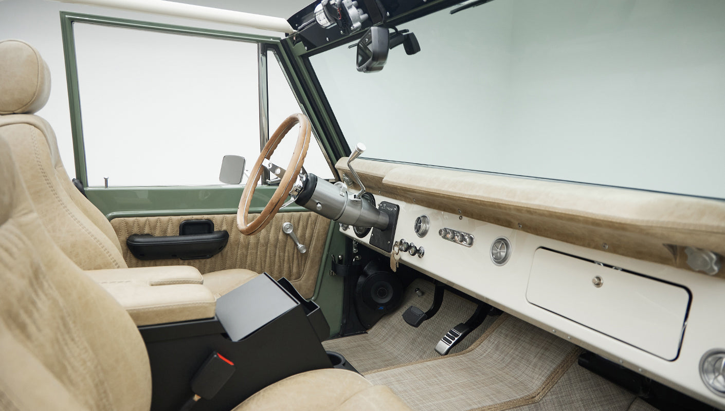 Interior front view of Classic Ford Bronco showing tan seats, steering wheel, and dashboard