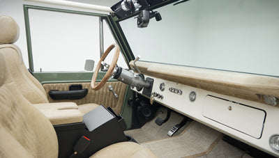 Interior front view of Classic Ford Bronco showing tan seats, steering wheel, and dashboard