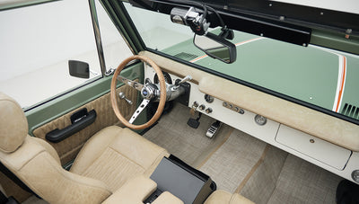Driver side interior view of Classic Ford Bronco showing steering wheel and tan seats