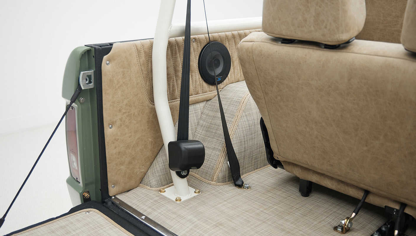 Rear interior view of Classic Ford Bronco showing seatbelt, roll bar, and speaker