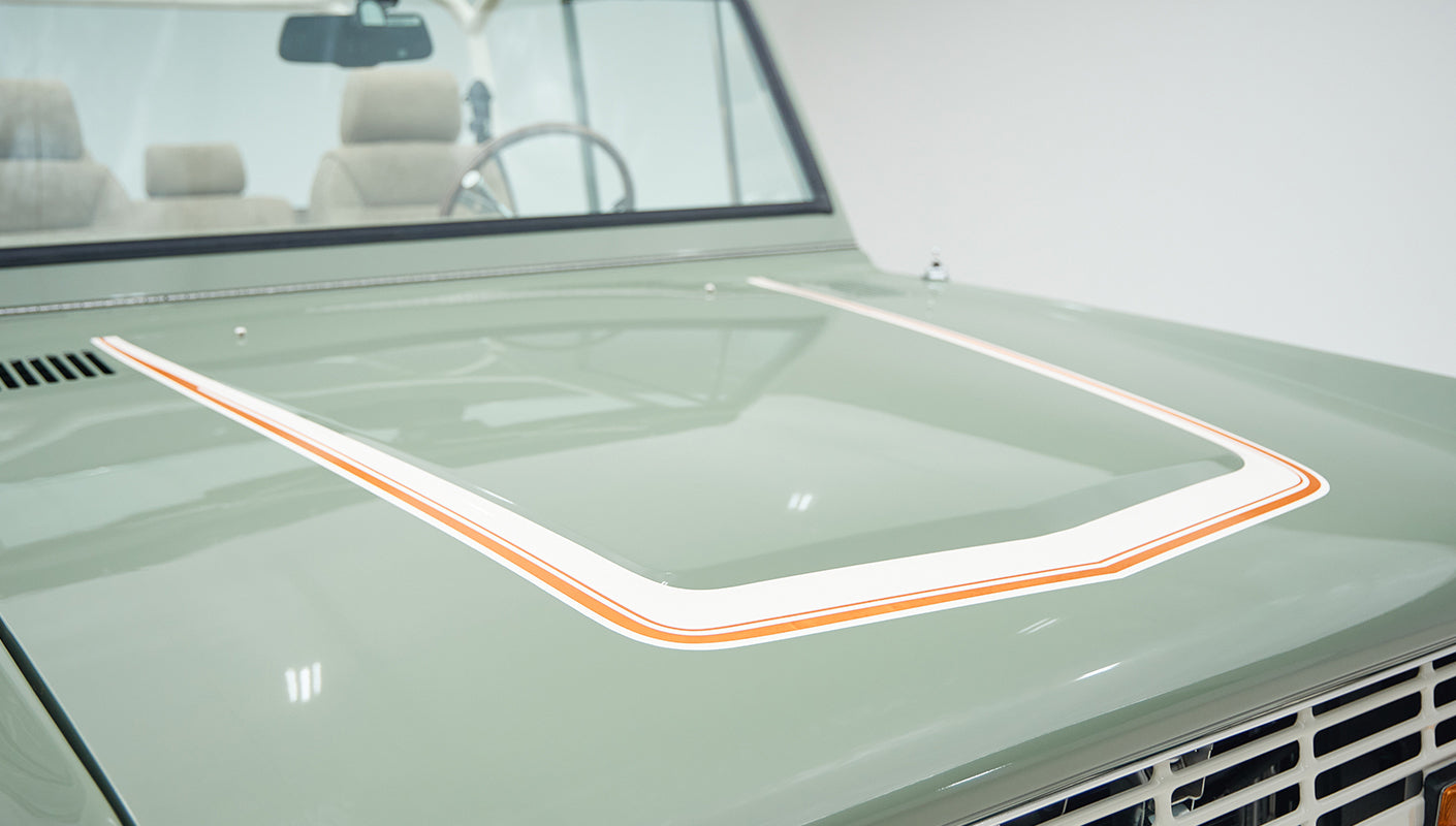 Close-up detail of boxwood green hood with white and orange pinstriping on classic Ford Bronco