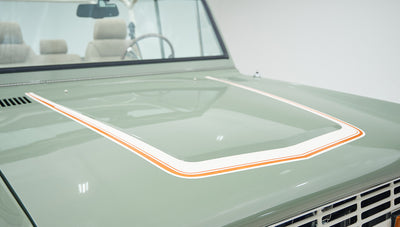 Close-up detail of boxwood green hood with white and orange pinstriping on classic Ford Bronco