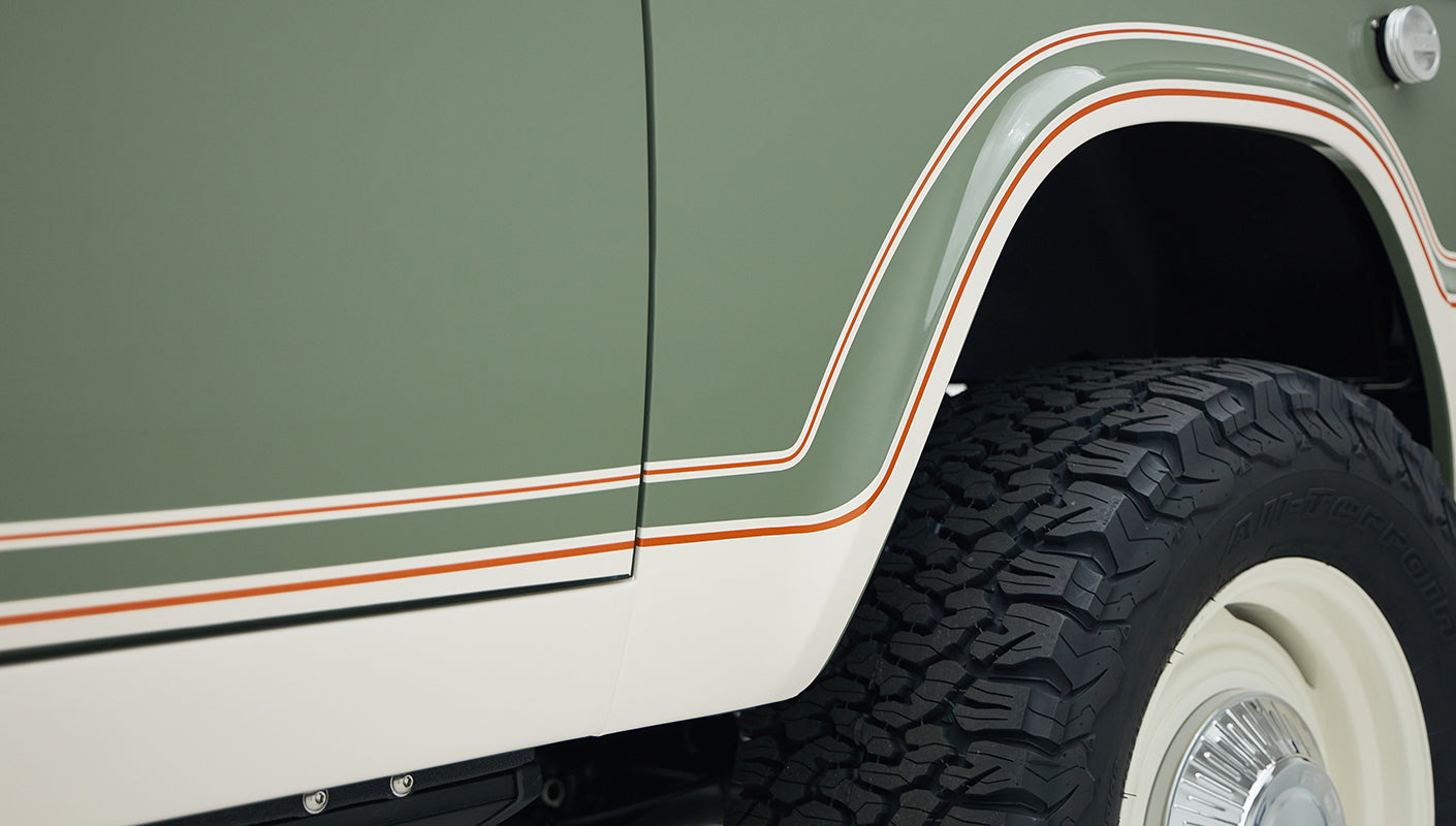 Close-up of Classic Ford Bronco boxwood green body with white and orange striped detailing over rear wheel
