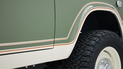 Close-up of Classic Ford Bronco boxwood green body with white and orange striped detailing over rear wheel