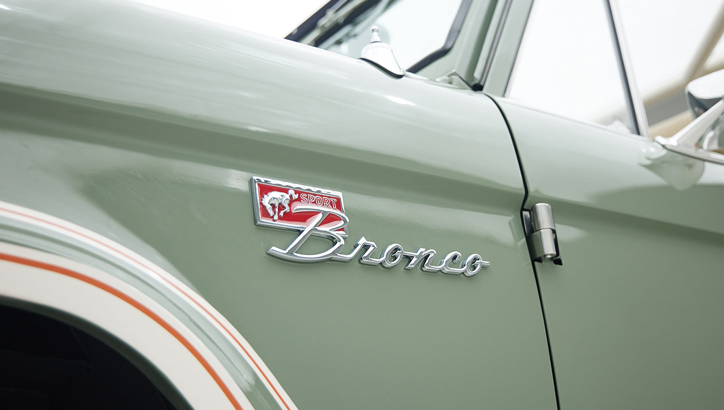 Classic Ford Bronco emblem on boxwood green body with white and orange pinstriping detail