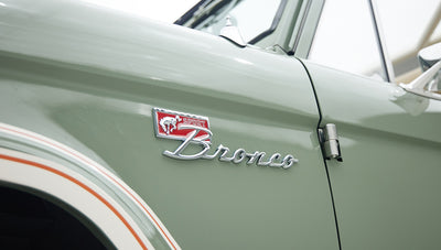 Classic Ford Bronco emblem on boxwood green body with white and orange pinstriping detail