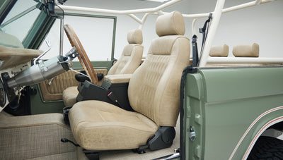 Classic Ford Bronco interior showing two front tan leather seats and center console
