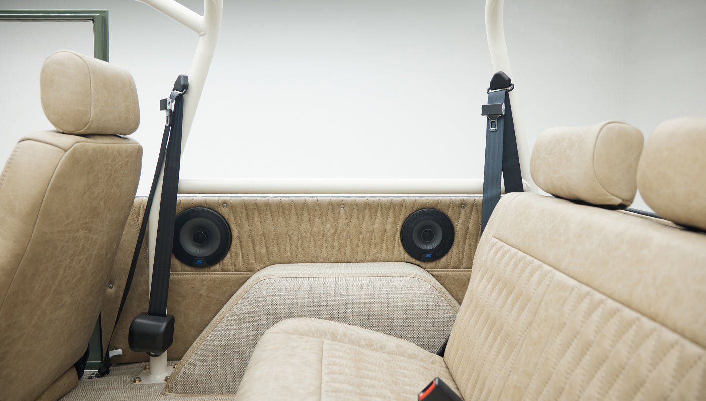 Interior rear seating area of Classic Ford Bronco with beige leather seats and built-in speakers