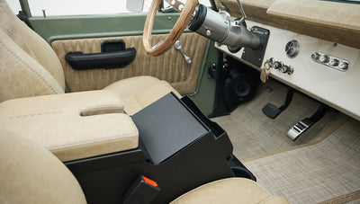 Center console with beige leather armrest and black storage compartment inside Classic Ford Bronco
