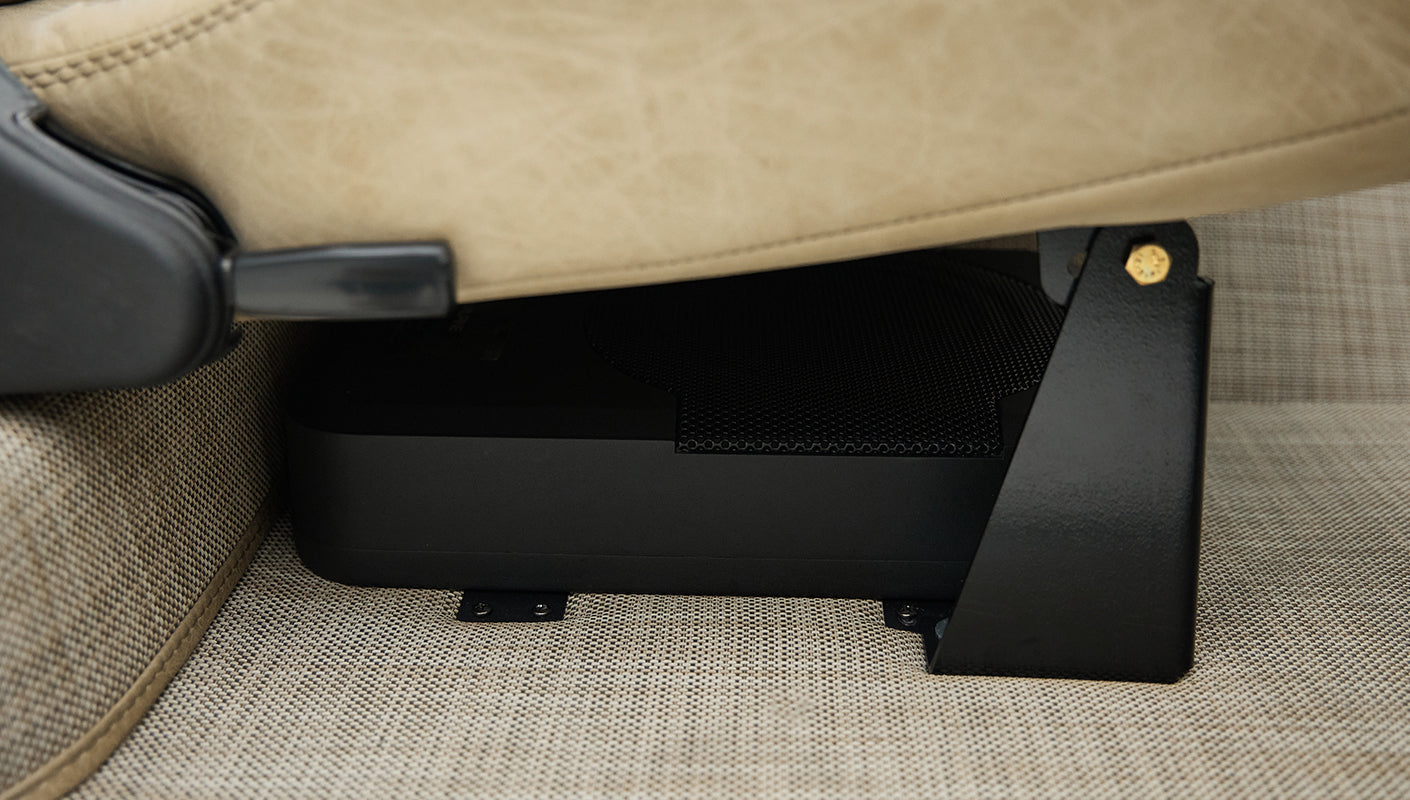 Underseat area showing black subwoofer enclosure beneath beige carpet in Classic Ford Bronco