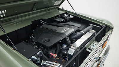 Engine bay of Classic Ford Bronco featuring modern 5.0 liter V8 engine with green exterior paint