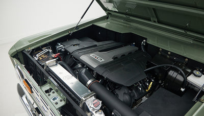 Angled view of Classic Ford Bronco engine bay with radiator and large black engine cover