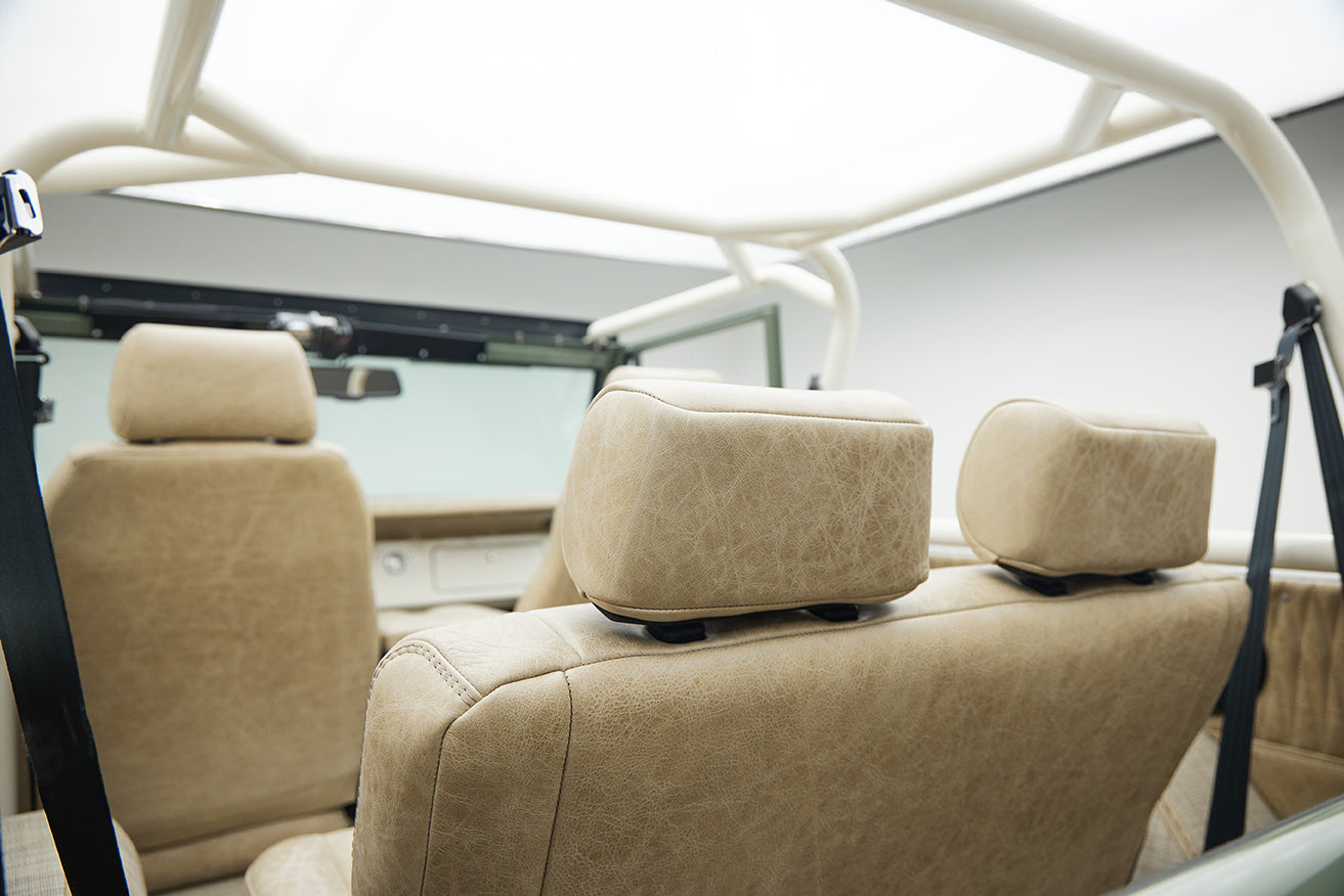 Interior rear seats with beige upholstery and white roll cage in Classic Ford Bronco