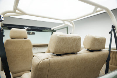 Interior rear seats with beige upholstery and white roll cage in Classic Ford Bronco