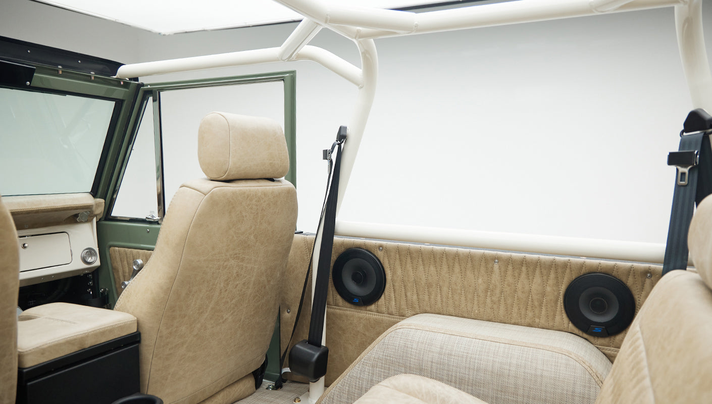 Side view of beige interior upholstery with speakers and seatbelt inside Classic Ford Bronco