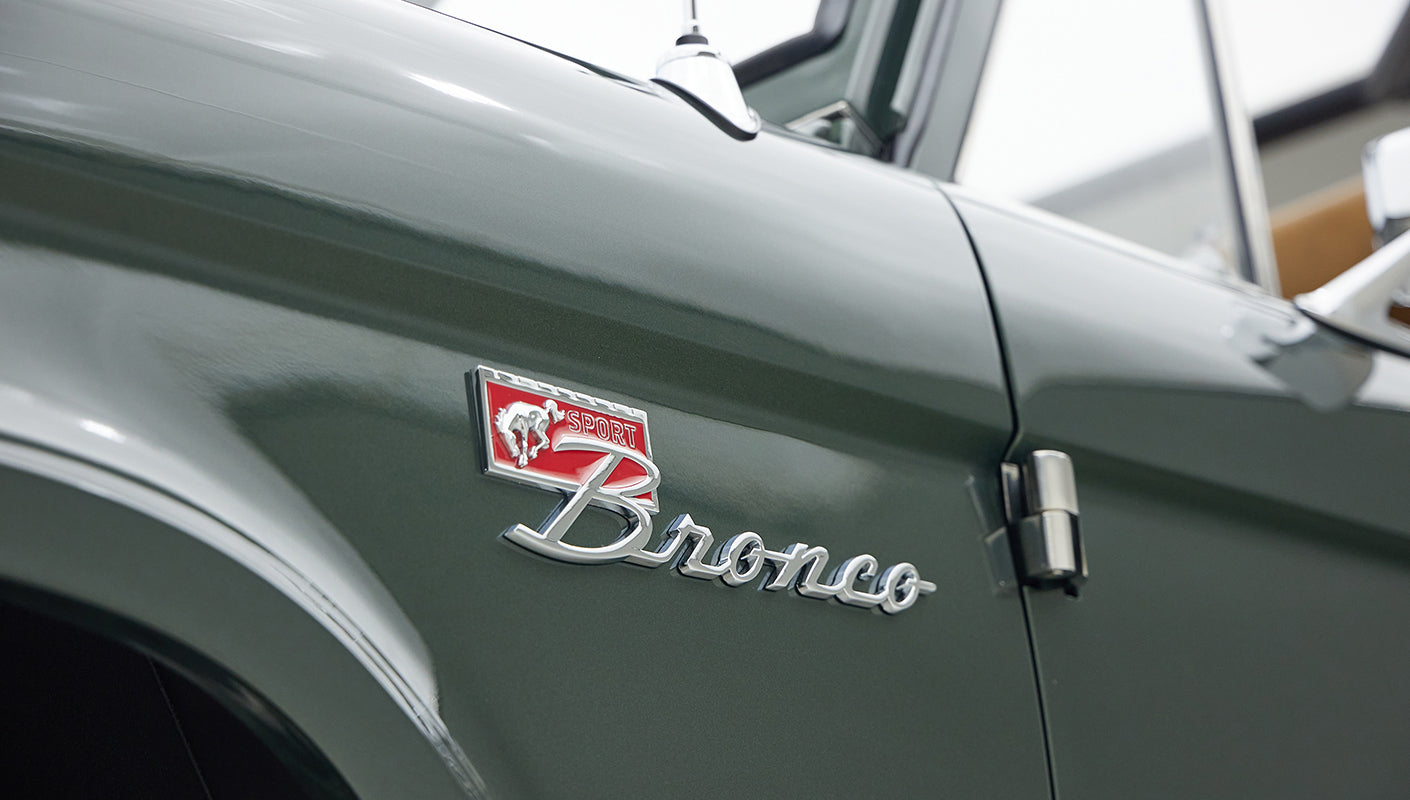 Classic Ford Bronco emblem with "Sport" badge on a green vehicle door panel.