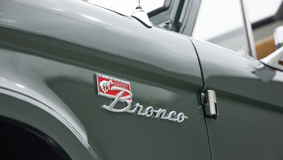 Classic Ford Bronco emblem with "Sport" badge on a green vehicle door panel.