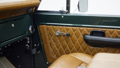 Classic Ford Bronco interior door panel with green trim and tan diamond-stitched leather upholstery.