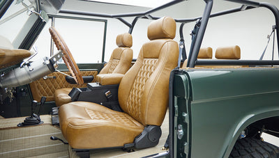 Classic Ford Bronco interior with tan diamond-stitched leather seats and a green exterior door panel.