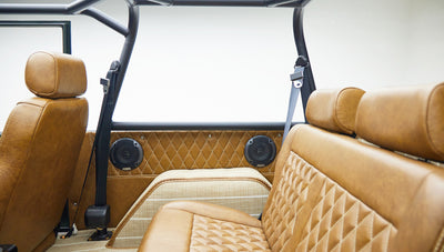 Interior view of a vehicle with quilted tan leather seats and black roll bars.