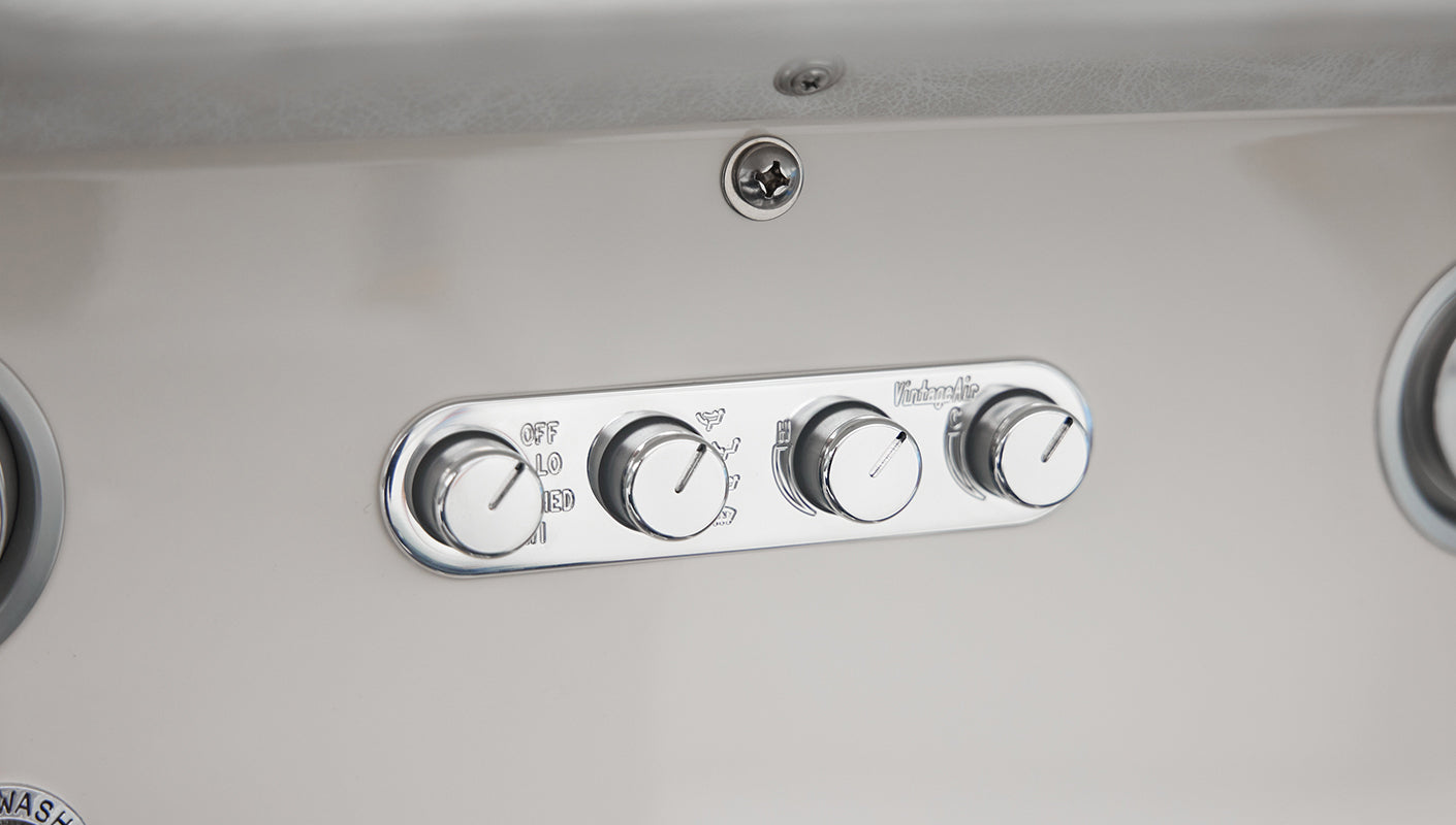 Chrome control panel with four knobs labeled VintageAir mounted on white Classic Ford Bronco dashboard