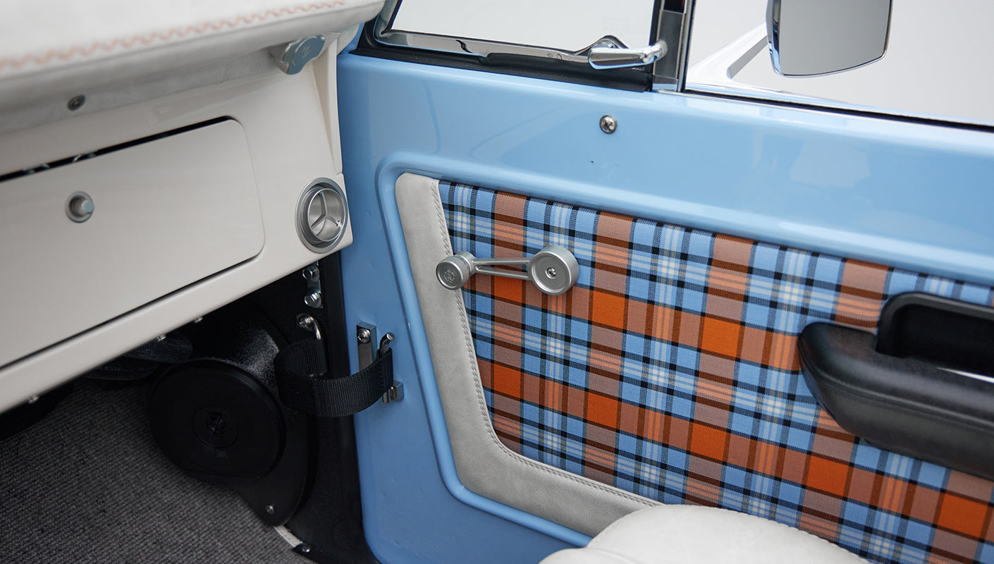 Close-up of blue and orange plaid door panel near white leather trim and speaker inside Classic Ford Bronco