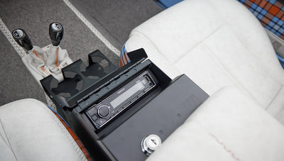 Center console of Classic Ford Bronco open to reveal Kenwood stereo system and cup holders